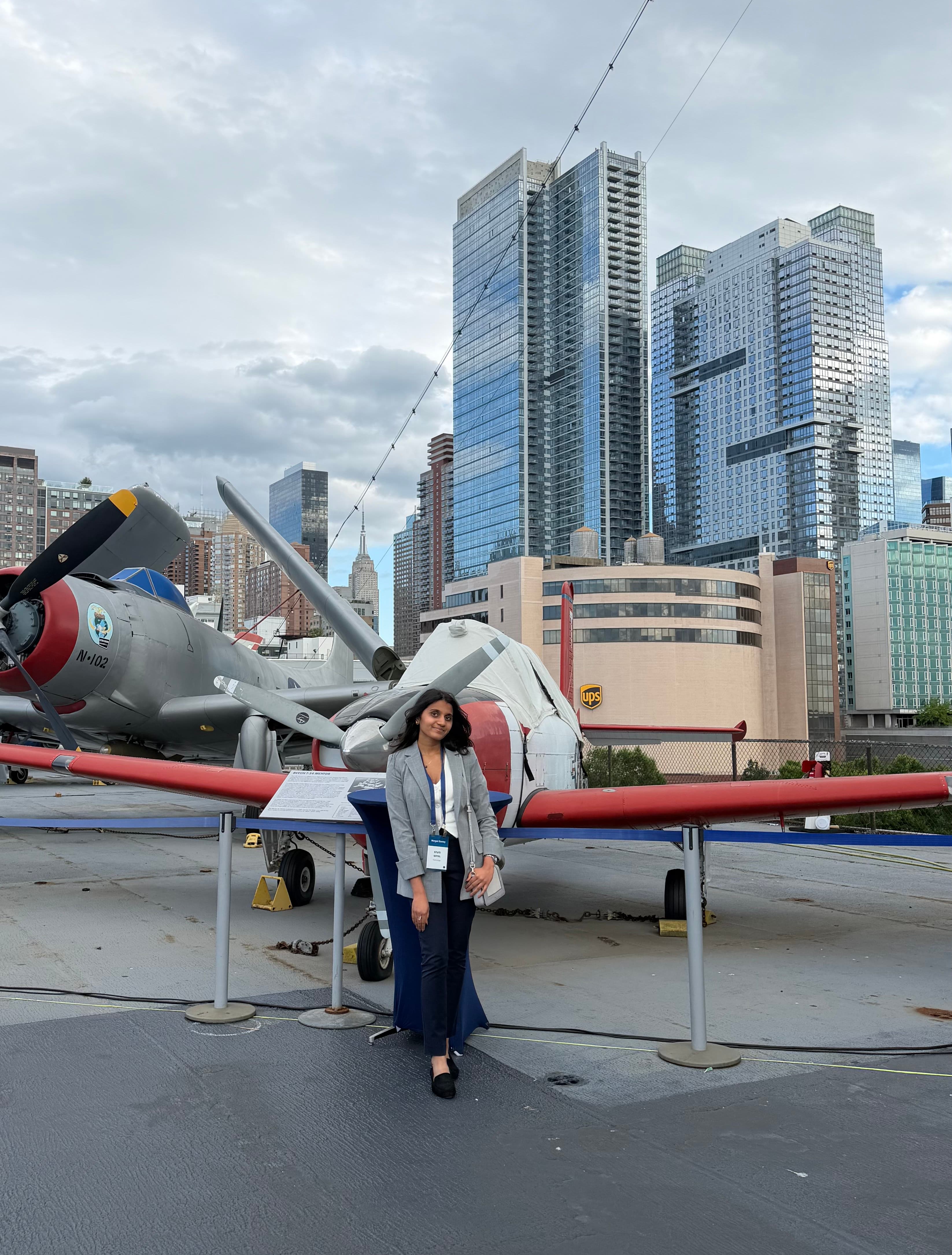 Stuti in New York with aircraft and the city skyline behind her